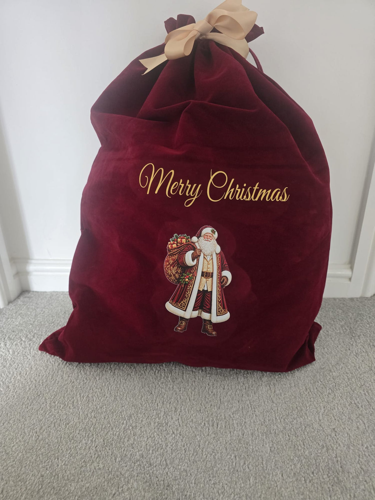 Personalised red velvet Christmas sack with gold lettering, Santa design and custom name, perfect for Christmas gifts.