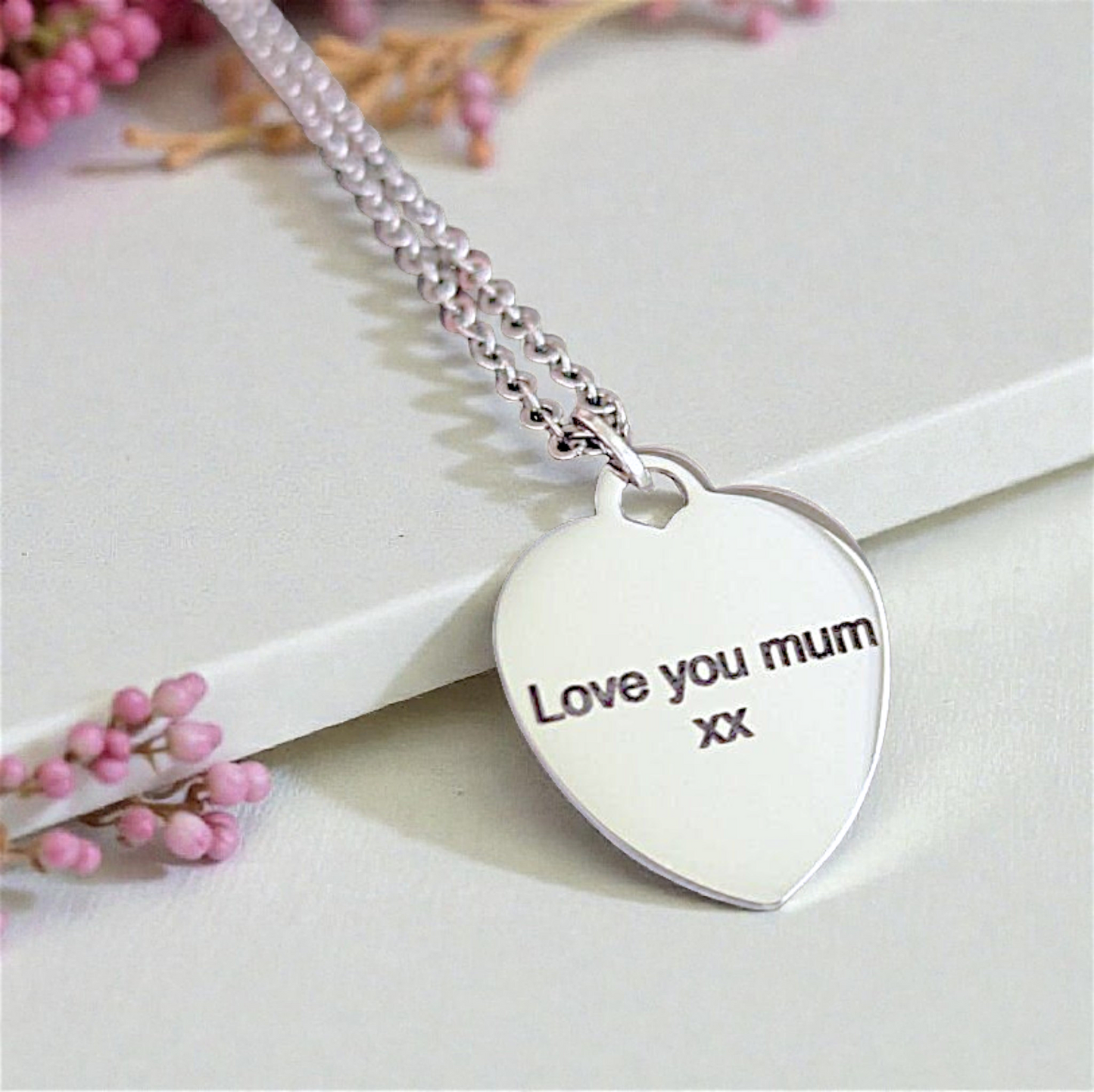 Silver heart-shaped pendant necklace with 'Love you mum' engraving on a light background