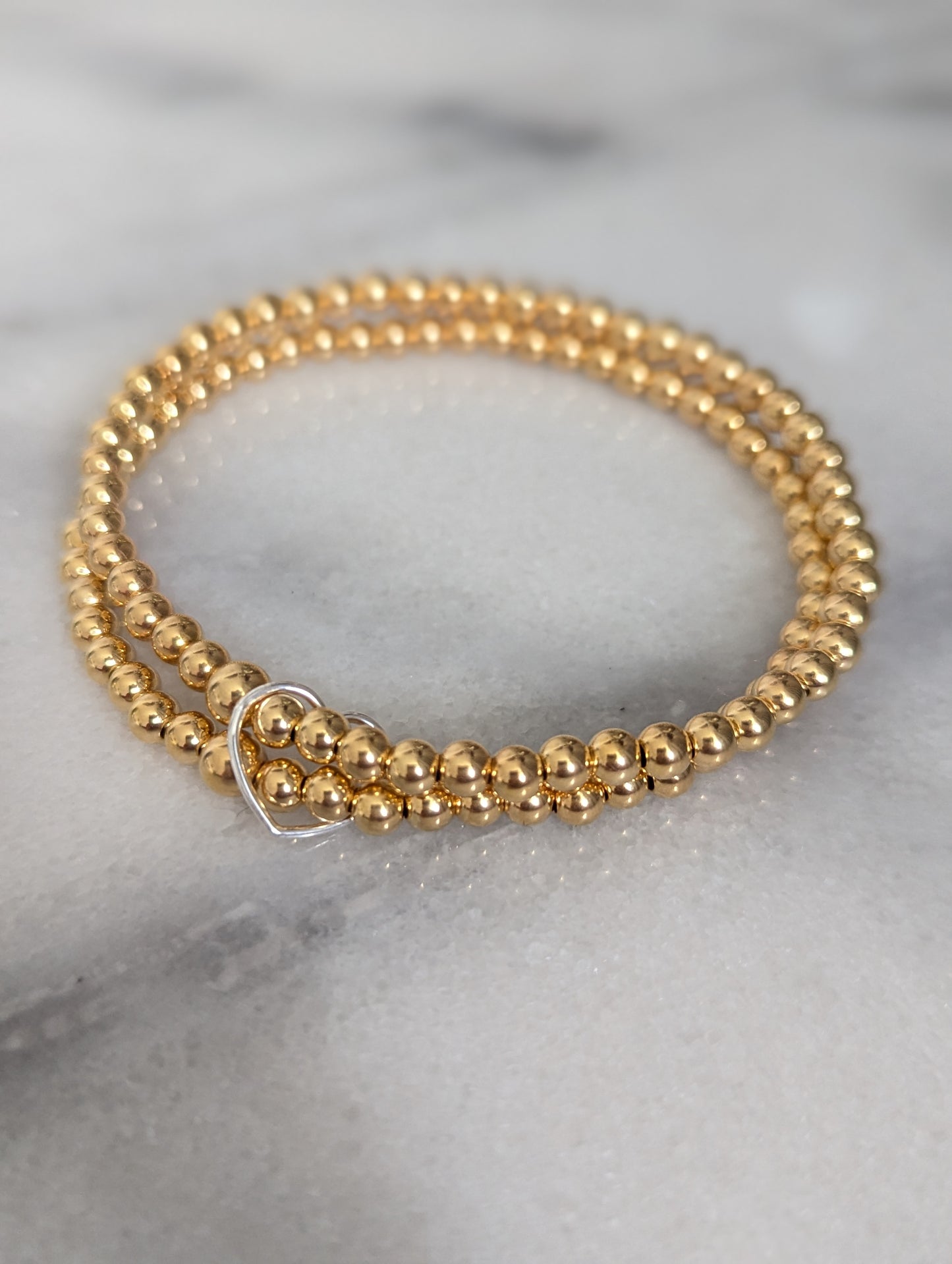 Double gold beaded bracelet, linked with a heart.