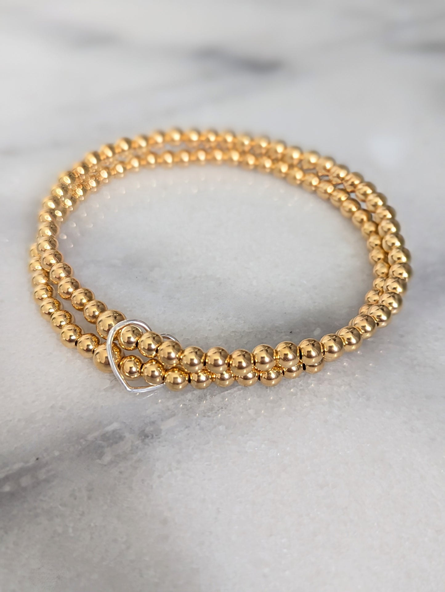 Double gold beaded bracelet, linked with a heart.