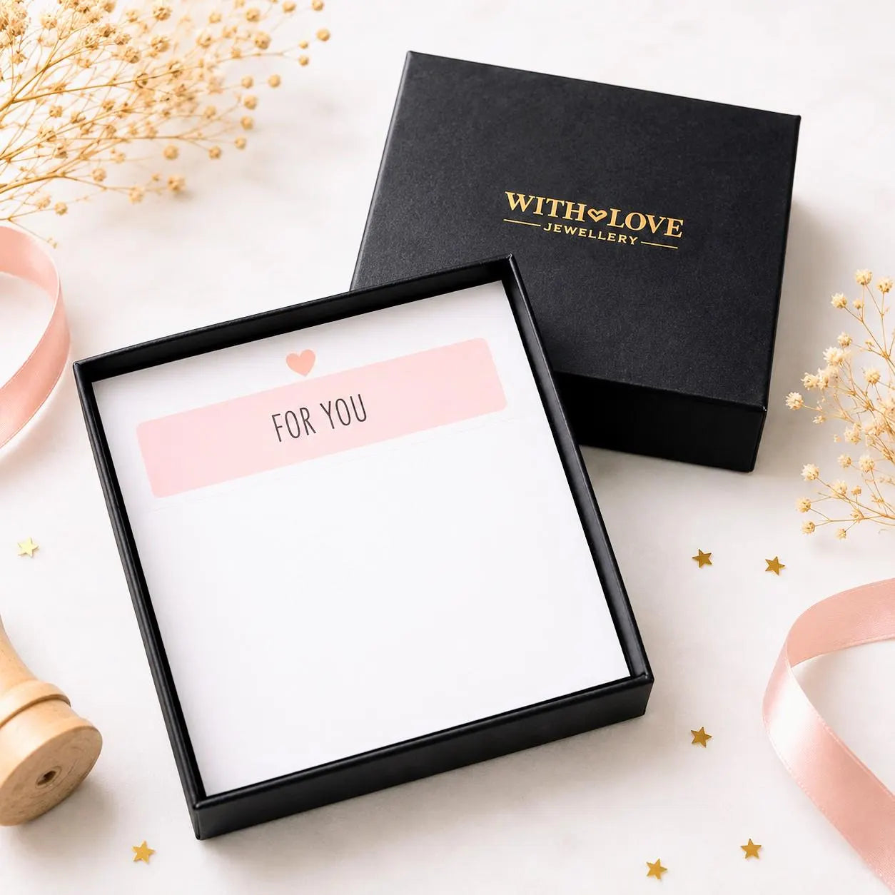 A black gift box with the brand name 'WITH LOVE JEWELLERY' in gold is shown open next to a closed box. The open box contains a white card with a pink 'FOR YOU' label, while the closed box has gold lettering.