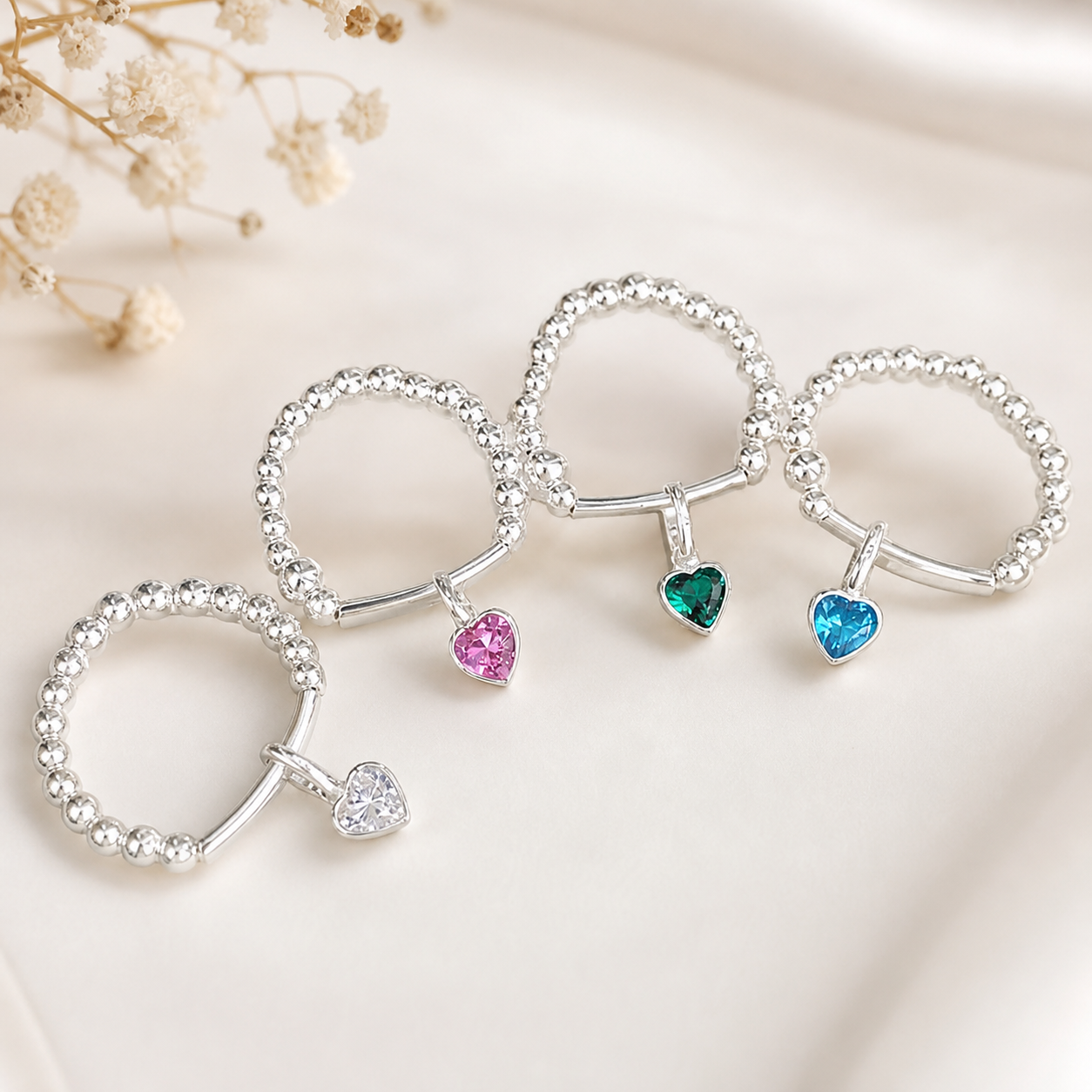 Set of silver rings with heart-shaped gemstones on a light background