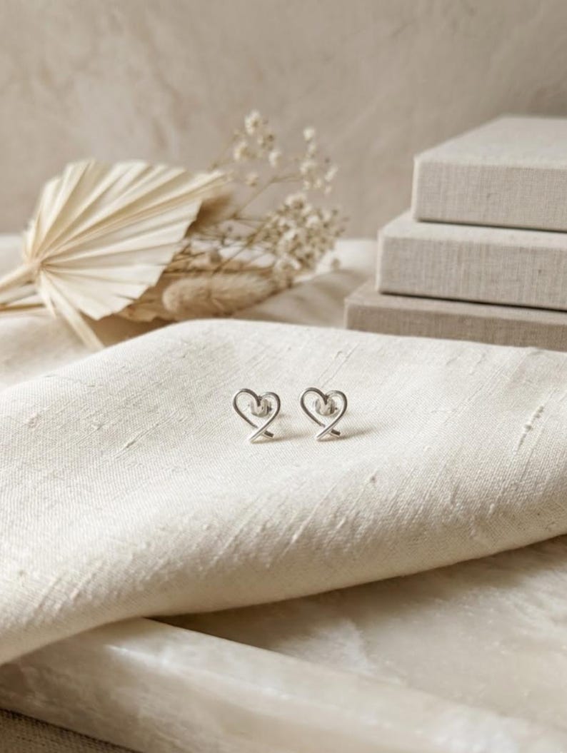 Heart-shaped earrings on a textured beige surface with a soft background