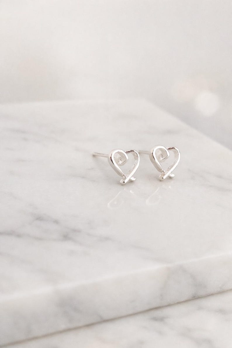 Heart-shaped silver earrings on a marble surface