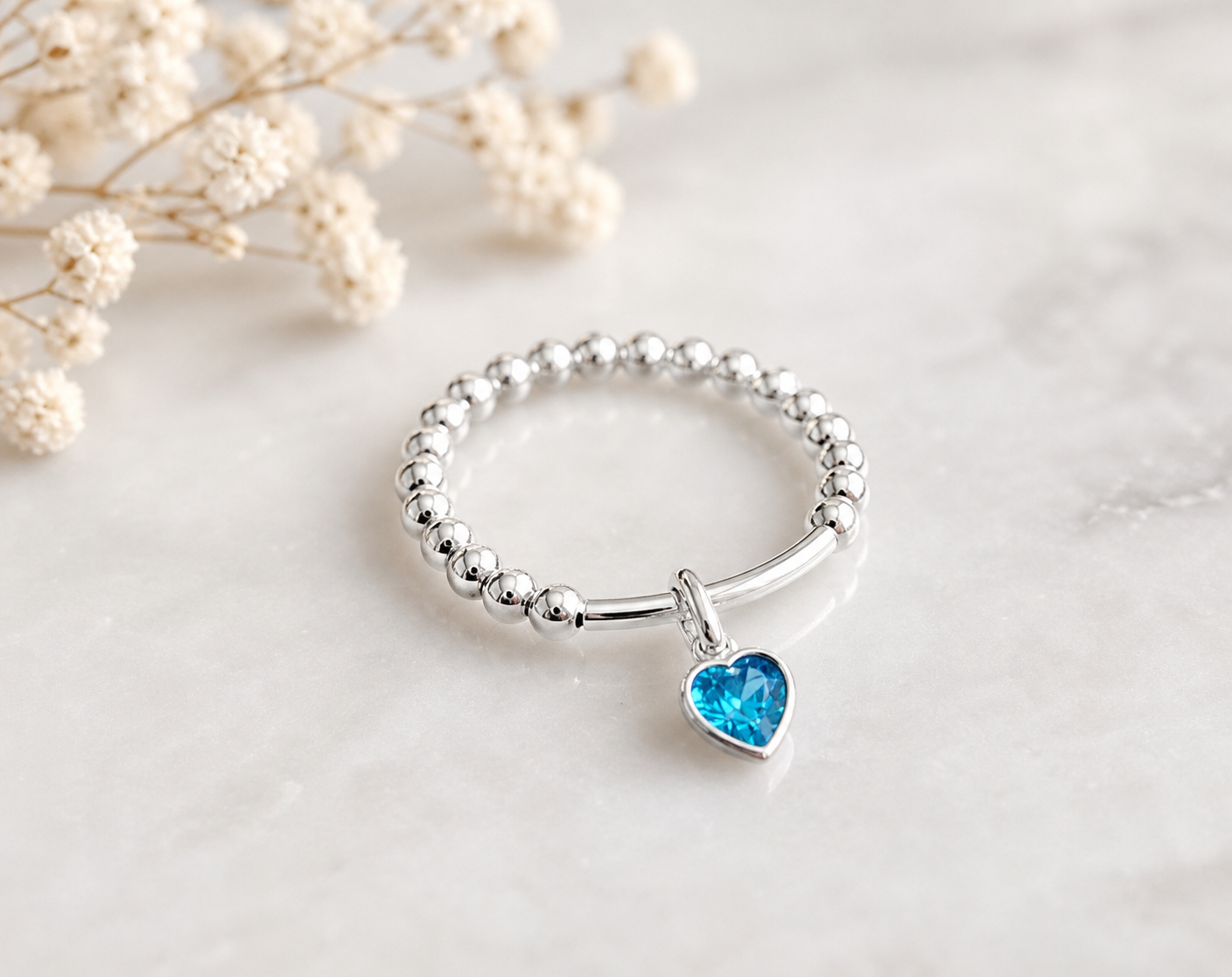 Silver ring with a blue heart-shaped gemstone on a light background