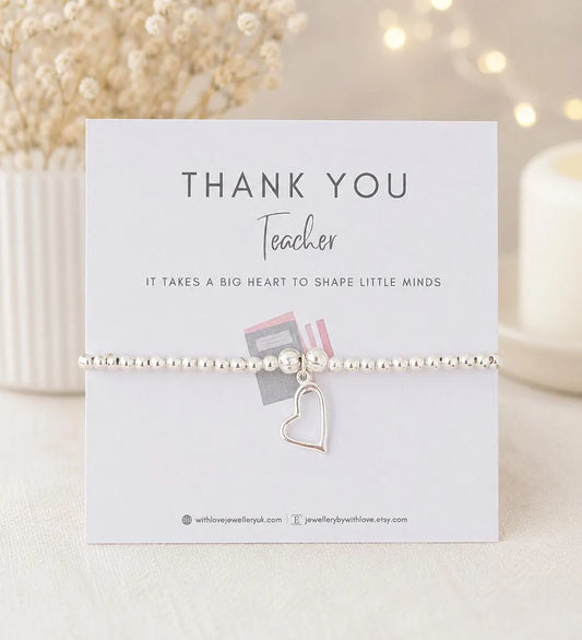 Bracelet with heart charm on a 'Thank You Teacher' card with decorative background